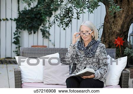 Stock Photo - Portrait of senior woman with book in garden. Fotosearch