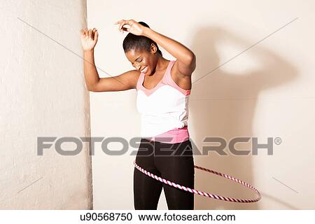 Stock Image - Portrait of young woman using plastic hoop. Fotosearch
