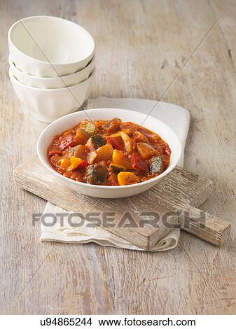 Picture - Ratatouille in white bowl. Garlic, onions, tomatoes and courgettes. Fotosearch