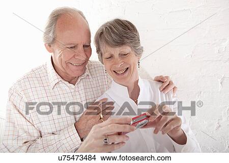 Picture - Senior couple holding digital camera. Fotosearch