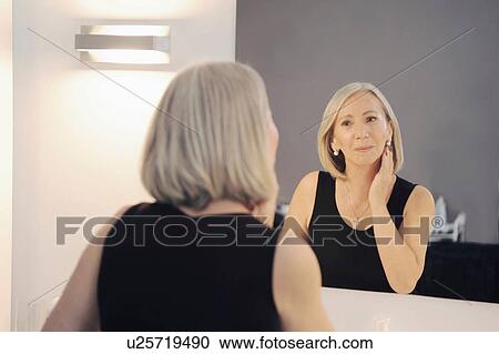 Senior woman looking at reflection in mirror View Large Photo Image Stock Image - Senior woman looking at reflection in mirror. Fotosearch