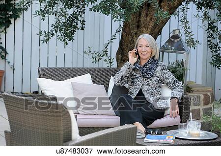 Stock Photo - Senior woman on cellphone in garden. Fotosearch