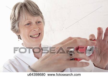 Stock Image - Senior woman taking photograph. Fotosearch