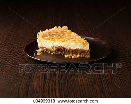 Stock Photo - Slice of toffee and pecan cheesecake on dark brown plate on dark wooden surface. Fotosearch