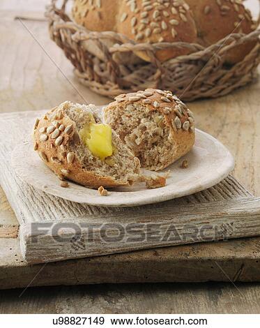 Stock Photo - Sunflower and honey wheat sheaf bread roll with butter. Fotosearch