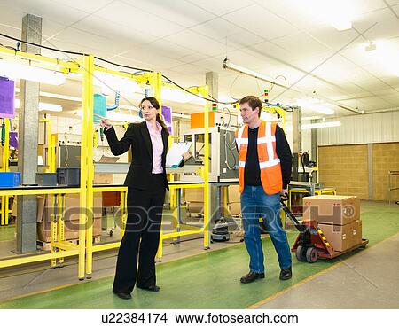 Picture - Supervisor directing worker in factory. Fotosearch