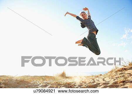 Stock Image - Teenage girl jumping on beach. Fotosearch