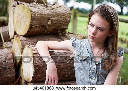 Teenage girl leaning on logs in forest View Large Photo Image Stock Photo - Teenage girl leaning on logs in forest. Fotosearch