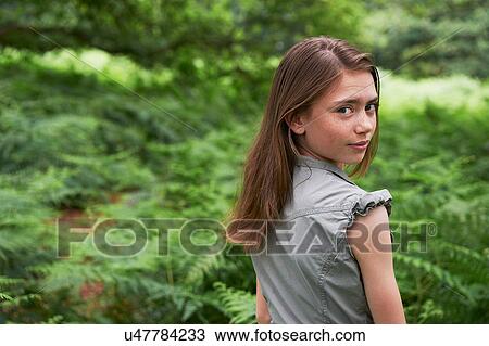 Stock Image - Teenage girl looking over shoulder in forest. Fotosearch