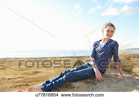 Picture - Teenage girl sitting on beach. Fotosearch