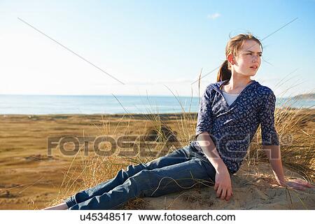 Stock Photo - Teenage girl sitting on beach. Fotosearch