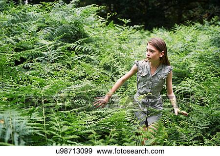 Stock Photo - Teenage girl walking through bracken in forest. Fotosearch
