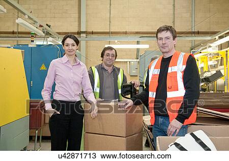 Stock Image - Three workers in electrical component factory. Fotosearch