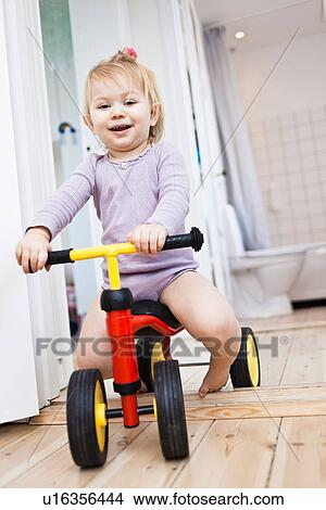 Picture - Toddler girl playing on tricycle. Fotosearch