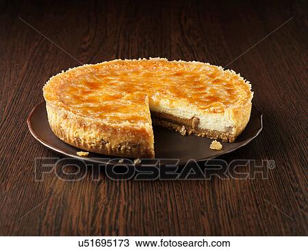 Stock Image - Toffee and pecan cheesecake on dark wooden plate and wooden surface. Fotosearch