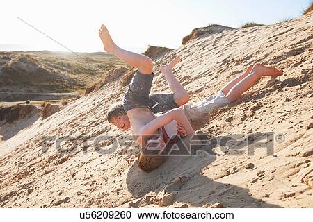 Two boys rolling on beach View Large Photo Image Stock Image - Two boys rolling on beach. Fotosearch