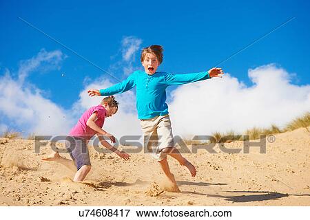 Stock Photo - Two boys running down sand dune. Fotosearch