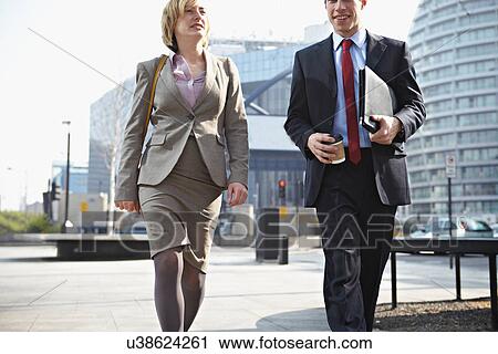 Two businesspeople walking in city View Large Photo Image Stock Image - Two businesspeople walking in city. Fotosearch