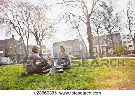 Two businesswomen sitting on grass in park View Large Photo Image Stock Photography - Two businesswomen sitting on grass in park. Fotosearch