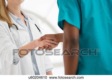 Two doctors shaking hands, mid section View Large Photo Image Stock Image - Two doctors shaking hands, mid section. Fotosearch