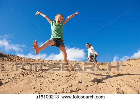 Two girls jumping on beach View Large Photo Image Stock Image - Two girls jumping on beach. Fotosearch