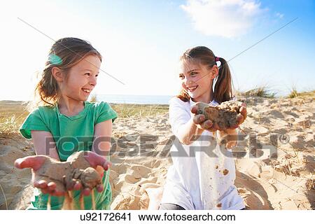 Stock Image - Two girls playing with sand. Fotosearch