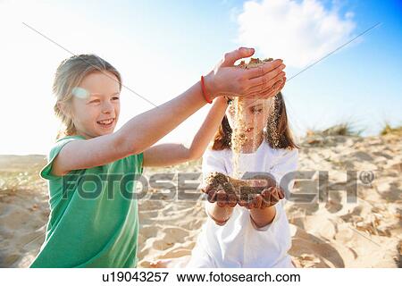 Two girls playing with sand View Large Photo Image Stock Photo - Two girls playing with sand. Fotosearch