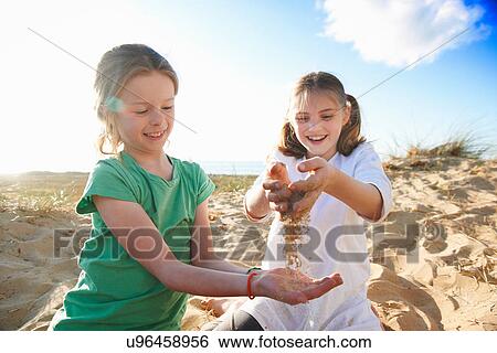 Two girls playing with sand View Large Photo Image Stock Photograph - Two girls playing with sand. Fotosearch