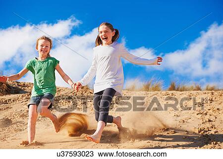 Two girls running down sand dune View Large Photo Image Stock Image - Two girls running down sand dune. Fotosearch