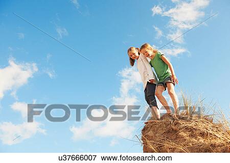 Two girls standing on edge of sand dune, low angle View Large Photo Image Stock Photo - Two girls standing on edge of sand dune, low angle. Fotosearch