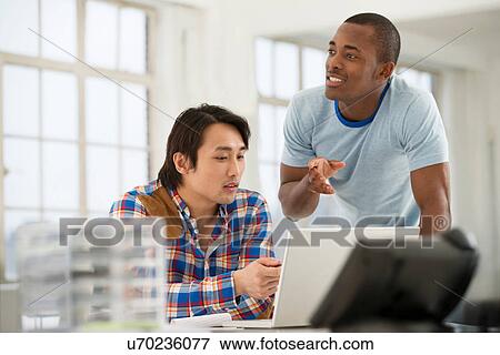Two male colleagues using laptop View Large Photo Image Stock Photo - Two male colleagues using laptop. Fotosearch