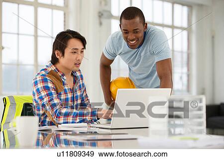 Stock Photo - Two male engineers using laptop. Fotosearch