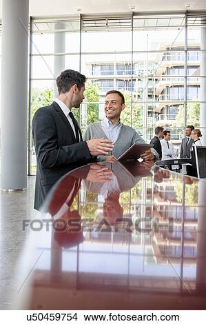 Two men in discussion at reception desk View Large Photo Image Picture - Two men in discussion at reception desk. Fotosearch