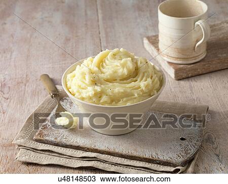 Stock Image - Vintage cheddar cheese potato mash with black pepper in cream dish on lime white board. Fotosearch