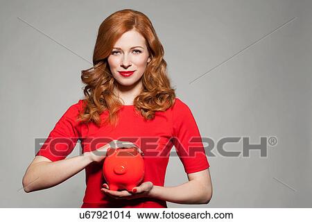 Picture - Woman holding red piggy bank. Fotosearch