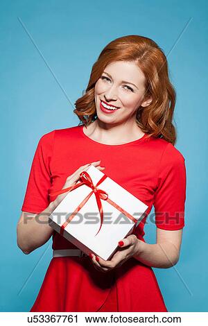 Stock Image - Woman holding white gift box with red bow. Fotosearch