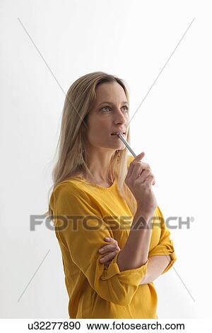 Woman in yellow top biting pen View Large Photo Image Stock Image - Woman in yellow top biting pen. Fotosearch