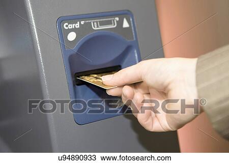 Stock Image - Woman inserting credit card into cashpoint. Fotosearch