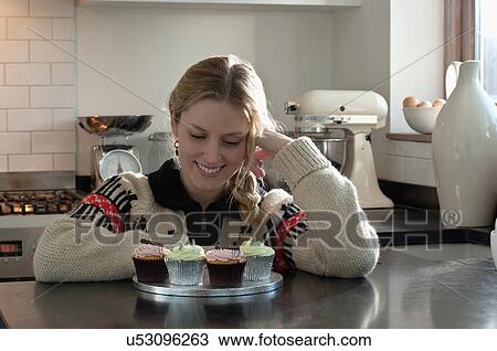 Woman kneeling admiring self-made cupcakes View Large Photo Image Stock Image - Woman kneeling admiring self-made cupcakes. Fotosearch