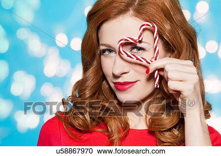 Stock Image - Woman looking through heart shaped candy. Fotosearch