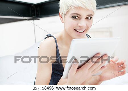 Woman lying on bed using digital tablet View Large Photo Image Stock Photograph - Woman lying on bed using digital tablet. Fotosearch