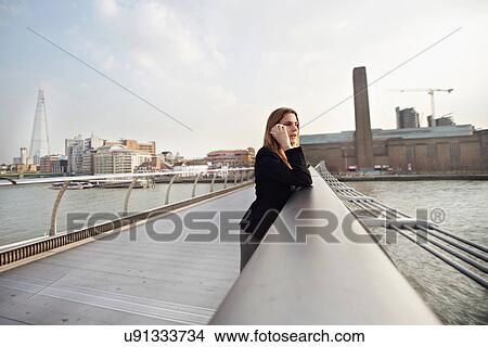 Woman on cell phone on Millennium Bridge, London, England, UK View Large Photo Image Picture - Woman on cell phone on Millennium Bridge, London, England, UK. Fotosearch