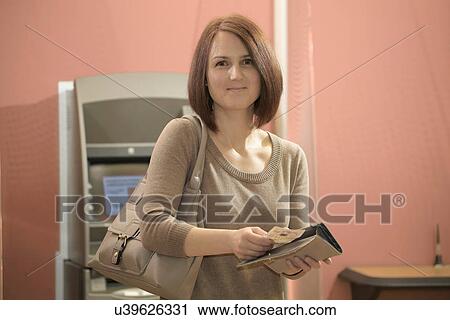 Woman putting banknotes into purse at cashpoint View Large Photo Image Stock Image - Woman putting banknotes into purse at cashpoint. Fotosearch