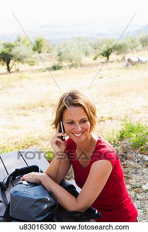 Woman sitting at picnic bench on cell phone View Large Photo Image Stock Image - Woman sitting at picnic bench on cell phone. Fotosearch