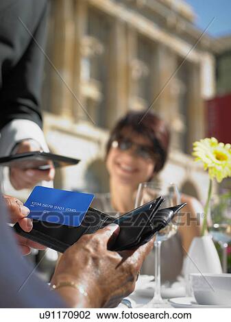 Woman smiling at friend making credit card payment View Large Photo Image Stock Image - Woman smiling at friend making credit card payment. Fotosearch