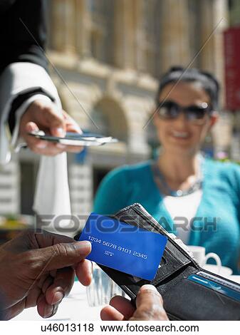 Woman smiling at friend making credit card payment View Large Photo Image Stock Photo - Woman smiling at friend making credit card payment. Fotosearch