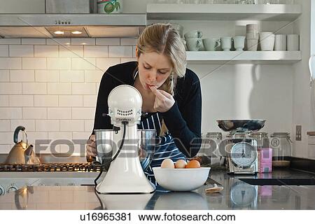 Stock Image - Woman tasting dough mix. Fotosearch