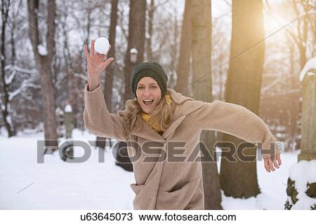 Woman throwing snowball in forest View Large Photo Image Stock Image - Woman throwing snowball in forest. Fotosearch