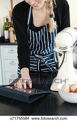 Woman using digital tablet to check recipe View Large Photo Image Picture - Woman using digital tablet to check recipe. Fotosearch
