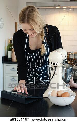 Woman using digital tablet to check recipe View Large Photo Image Stock Photo - Woman using digital tablet to check recipe. Fotosearch